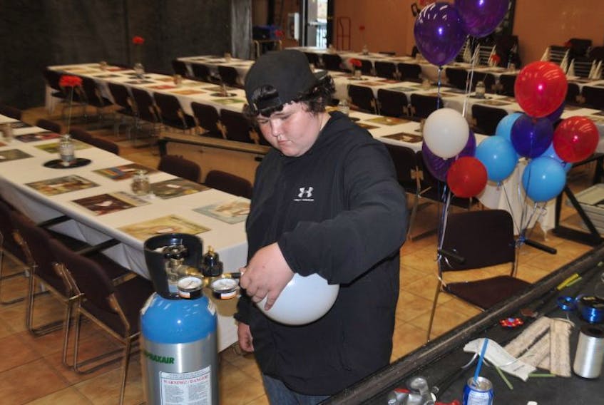 Kyle Degaust fills up balloons in preparation for the survivor reception, part of the Pictou County Relay for Life activities planned for today.