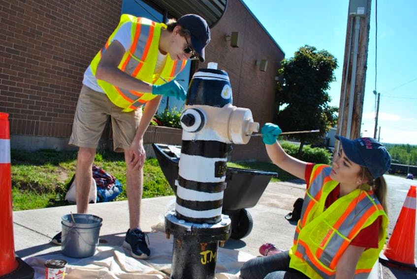 Summer students James MacDonald and Jane Ford paint a fire hydrant in Stellarton on Wednesday. 