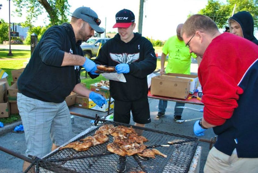 Volunteers pack cooked chicken into foil bags at the New Glasgow Kinsmen Club chicken barbecue on Friday.