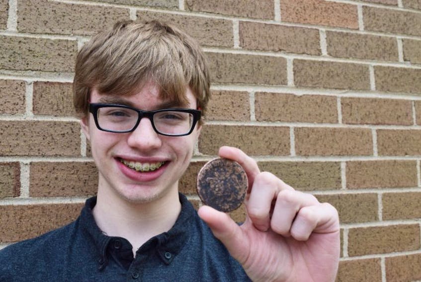 Kieran Bent holds a 1765 Russian coin he found on a beach along the East River in Abercrombie on Saturday.