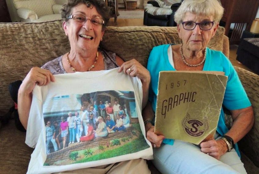 Teresa Morris displays a T-shirt from an earlier Stellarton High School reunion and Margie Holmes holds the yearbook for the Class of 1957, which will celebrate its 60-year reunion on the weekend. (Rosalie MacEachern photo)