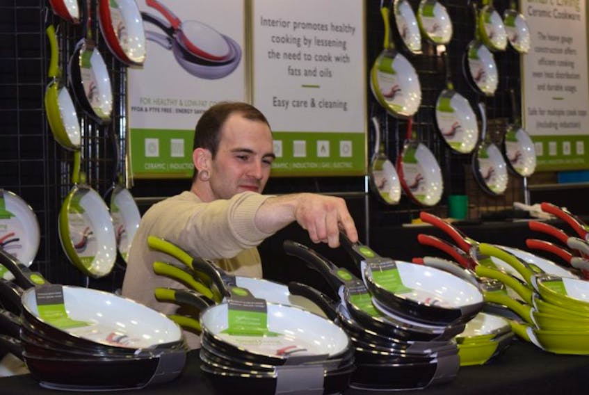 Tyler Clark adjusts the display of ceramic cookware at the Pictou County Home Show on Saturday afternoon.
