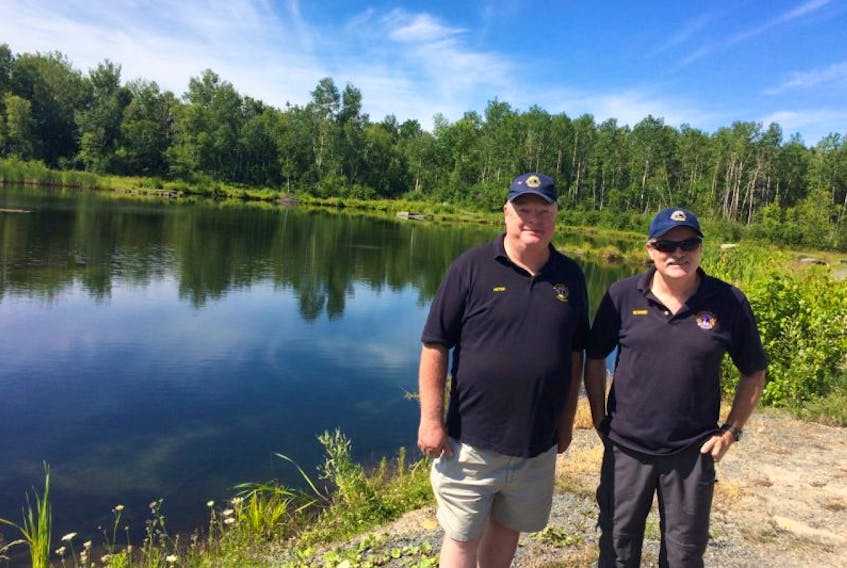 Peter Boyles, left, Rob Forbes, right, both members of the Pictou and Area District Lions Club, stand beside Quarry Pond near Browns Point in Pictou which the club had hoped to turn into a green space for the town.