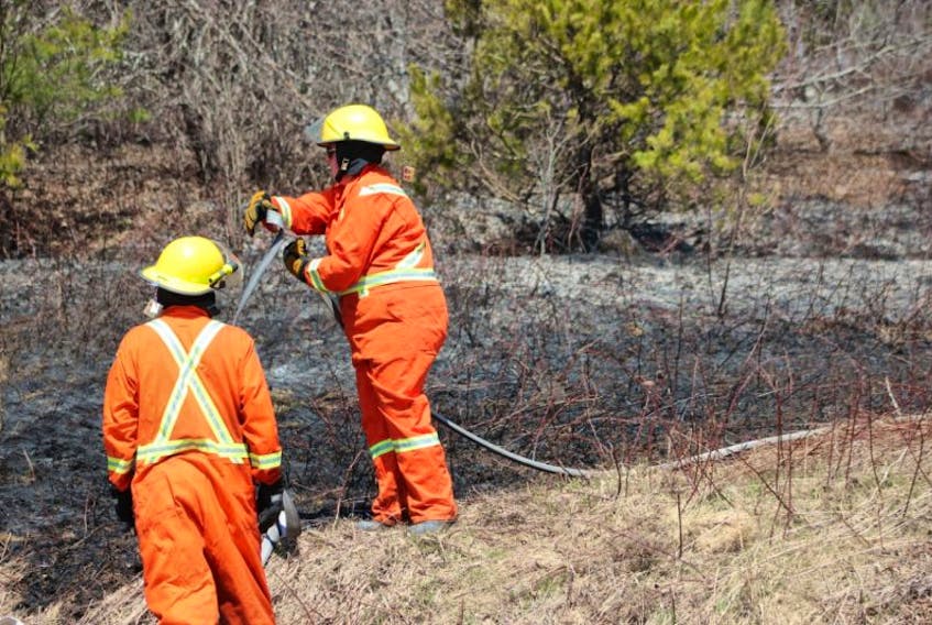 Firefighters collect equipment after extinguishing a brush fire in the Glencoe, Pictou County area on Tuesday. 