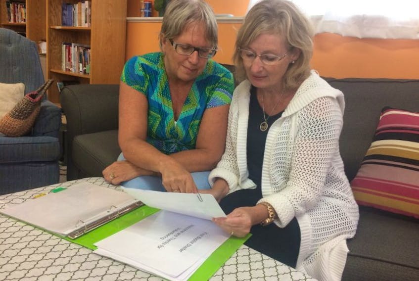 Donna Cooper, left, and Ellen Margeson, both committee volunteers with the First Baptist Temporary Homeless Shelter, look over schedules and their volunteer list.
