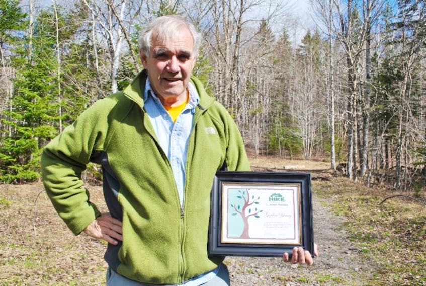 Dr. Gordon Young is shown at the Six Mile Brook Trail with an award he received from Hike Nova Scotia for his work promoting hiking and trail development.