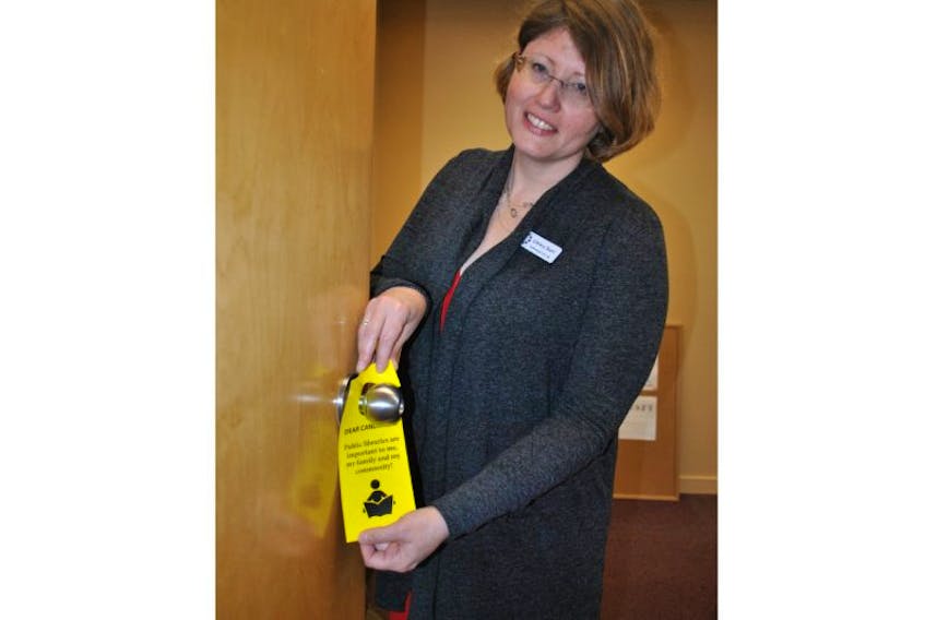 Community services librarian Trecia Schell places a door hanger, hoping that people will use them to spark conversation with provincial election candidates about increasing library funding.