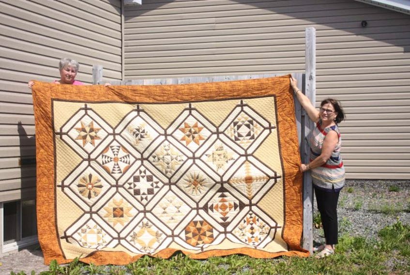 Eddie Kennedy, left, quilt raffle coordinator, and Liz Chenell, guild president, hold a quilt, made by Kennedy, that will be raffled off as a fundraiser for the guild. Tickets will be sold at the show for $1 each. The draw will be Sunday afternoon. 