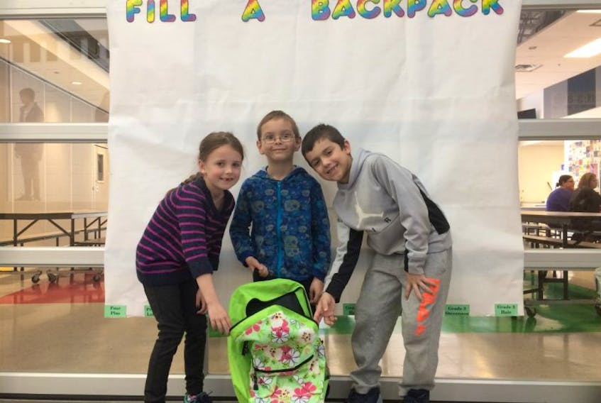 Zoe Chisholm, JT Cameron and James MacKay, Grade 2 students at New Glasgow Academy, prepare to Fill a Backpack to help families fulfill nutritional needs over the weekend. 