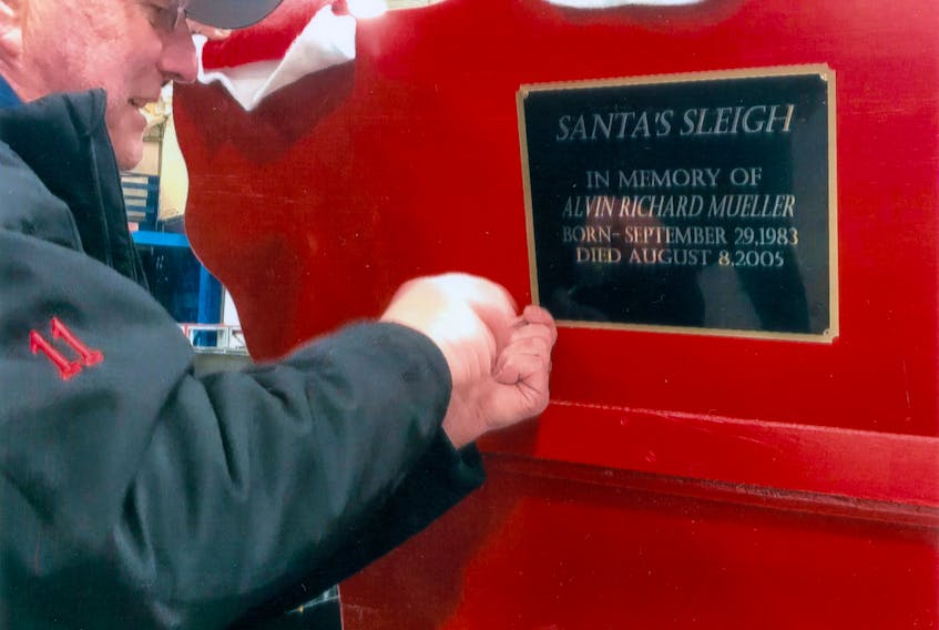 David White of the New Glasgow Fire Department attaches a plaque to Santa’s sleigh in honour of Alvin Richard Mueller, who requested to see Santa and a fire truck in 2004. Since this time, the fire department has been making its annual Christmas Eve run throughout the town.