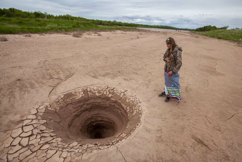 F
Grassroots grandmother and water keeper Marian Nicholas looks into a large hole that had formed on a mudflat near the site of the Alton natural gas project, along the Shubenacadie River, near Fort Ellis, N.S., Tuesday June 2, 2020. Nicholas, who was maintaining the treaty truck house nearby, had earlier said a fisherman had seen bubbles in the area but had not seen this before.