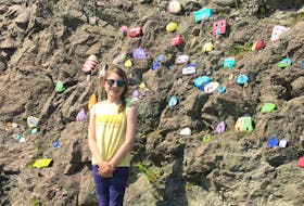 Shauna Strickland’s daughter, Emily, poses with the rock art wall in Burgeo. Strickland hopes to create a similar wall in Martin’s Corner.