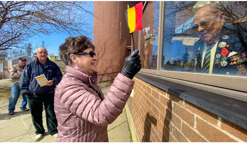 Rita Doucette smiles at Alcide LeBlanc while waving a Belgium flag. A few legion members and others gathered outside Veterans Place in Yarmouth for a few minutes on March 21 to sing Happy Birthday to LeBlanc, who was marking his 100th birthday. TINA COMEAU PHOTO