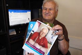 <p>Norman Richard holds up two CNIB publications that feature him and his story.</p>