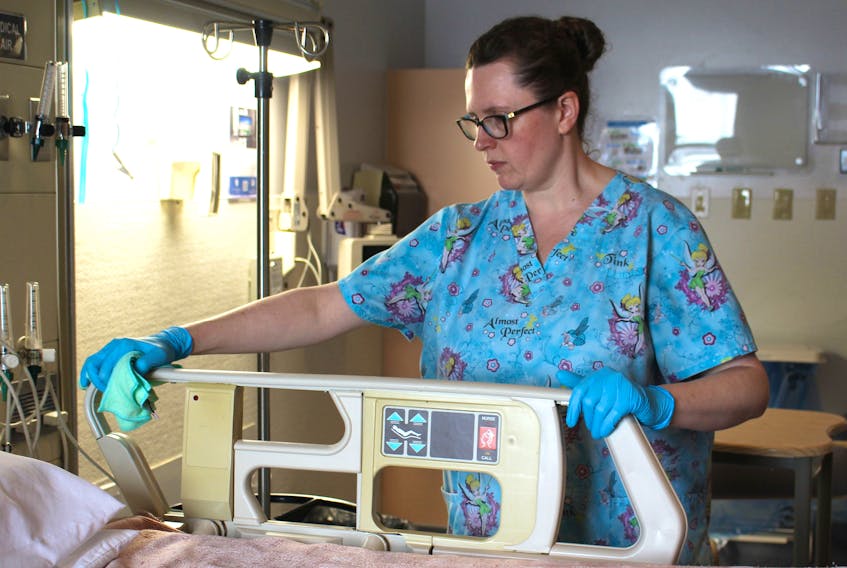 Laurie MacInnis, a utility worker with the environmental services department at the Cape Breton Regional Hospital, cleans a bed rail on one of the hospital’s inpatient units. Nova Scotia's Chief Medical Officer of Health Dr. Robert Strang said protective gloves could cause more harm than good. CONTRIBUTED