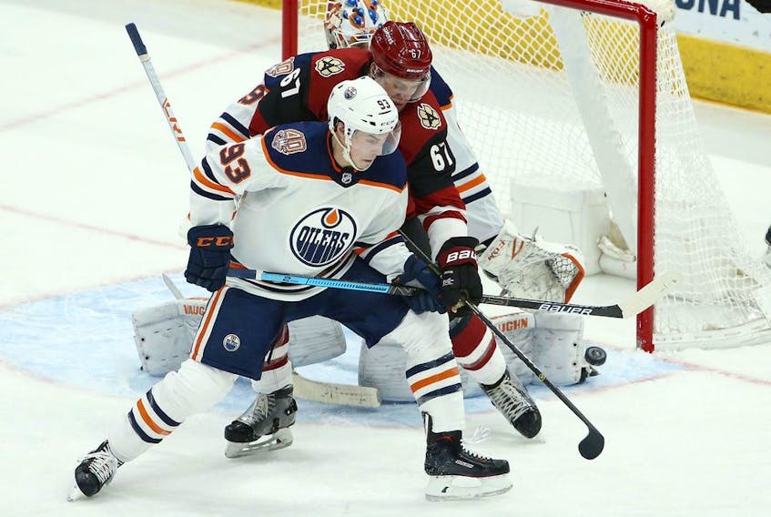 Edmonton Oilers center Ryan Nugent-Hopkins (93) and Arizona Coyotes left wing Lawson Crouse (67) try to get a stick on the puck during the third period of an NHL hockey game Wednesday, Jan. 2, 2019, in Glendale, Ariz. The Oilers defeated the Coyotes 3-1.