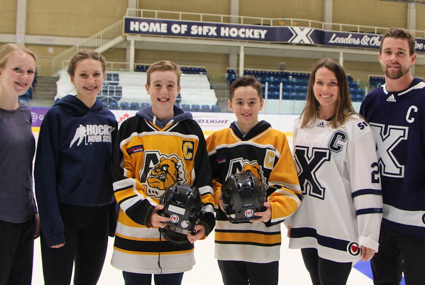 The St. F.X. X-Men and X-Women hockey teams have a special logo on their jerseys this season, one in honour of the late Oliver Smith. His teammates and friends with the Antigonish Peewee ‘AAA’ Bulldogs are wearing decals on their helmets. Here, Oliver’s sisters’ Emma (left) and Megan, join his teammates and co-captains Brady Peddle and Trent Stewart, along with St. F.X. captains Lydia Schurman and Mark Tremaine, for a photo. Corey LeBlanc