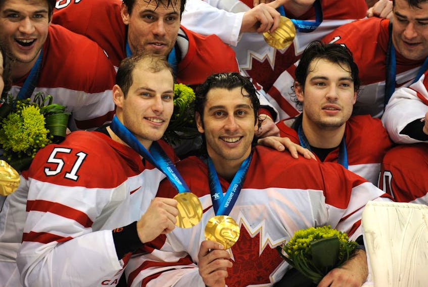 Canada's goaltender Roberto Luongo, centre, and Ryan Getzlaf, left, proudly display their gold medals after defeating the United States 3-2 in overtime in the Olympic men's hockey final in Vancouver on Feb. 28, 2010.