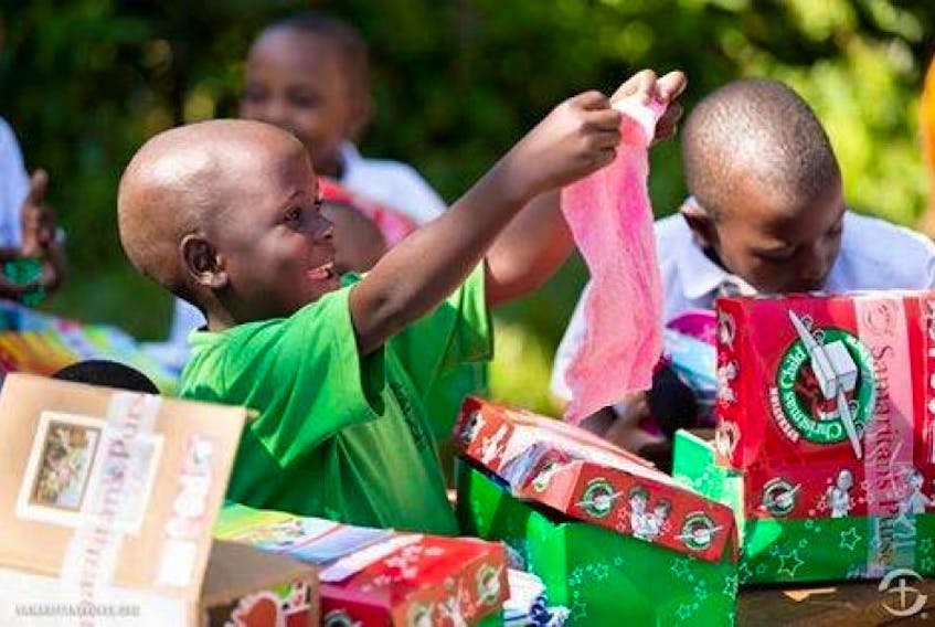 Photo from Operation Christmas Child's Facebook page of children opening shoeboxes filled with gifts and hygiene items.