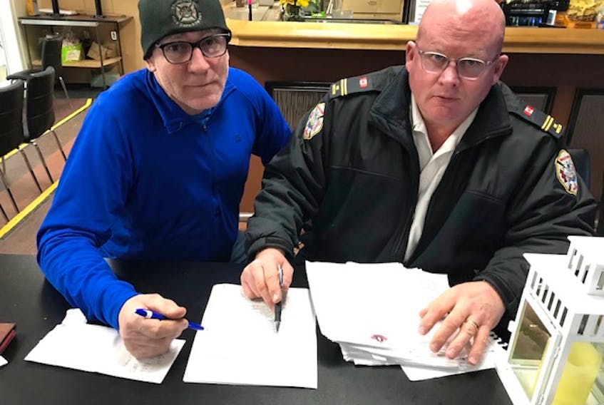 Peter MacDonald, left, and Winston Bryan, co-chairmen of the upcoming Canadian FireFighters Curling Championships in Charlottetown, go over team lists as preparations continue for the national competition. The Charlottetown Curling Complex is hosting the event from March 26-April 4. 
Bill McGuire/Special to The Guardian