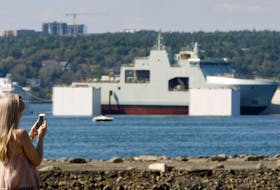A spectator at the Africville Museum Baptist church grounds takes a photo of the Bedford Basin as the float test for the Future HMCS Harry DeWolf gets underway Saturday afternoon.
