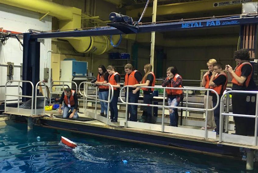 Students from Clarenville High School watch their boat navigate the waters of a flume tank.