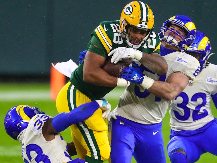Green Bay Packers running back AJ Dillon (28) runs with the ball while Los Angeles Rams safety Nick Scott (33) and linebacker Troy Reeder (51) attempt to tackle him Saturday at Lambeau Field. 
