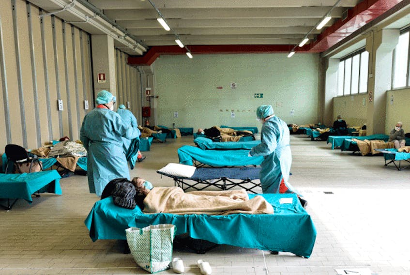  Medical personnel care for patients in an emergency temporary room, set up to ease pressure on the healthcare system caused by the coronavirus pandemic, at a hospital in Brescia, Italy, on March 13, 2020.
