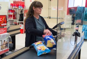 Kim Gamble, a front-end supervisor with Atlantic Superstore scans groceries behind plexiglass at the store on Joseph Howe Dr. in Halifax on Monday. Ryan Taplin - The Chronicle Herald