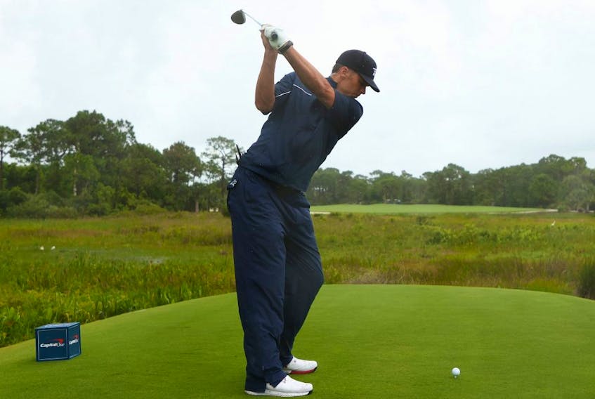 Wearing bulky rain pants to hide a rip in his trousers, Tom Brady of the Tampa Bay Buccaneers plays his shot from the ninth tee during The Match: Champions For Charity at Medalist Golf Club on May 24, 2020 in Hobe Sound, Fla.