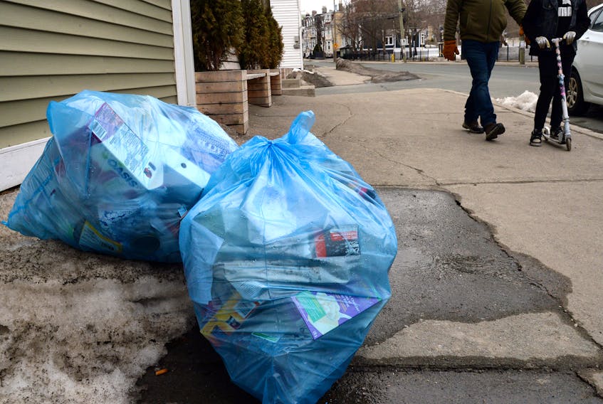 Two people make their way past uncollected recycling on Military Road Monday afternoon. For some St. John’s residents, bags of recycling are beginning to pile up since pick-up was suspended March 17. -KEITH GOSSE/THE TELEGRAM