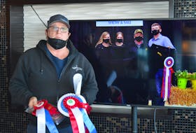 Donald MacRae, owner of MacRae’s Backhoeing and Trucking, poses virtually with the grand champion on Friday after bidding successfully on the grand champion at the Easter Beef Show and Sale auction in Charlottetown. Due to public health guidelines, the bidders and farmers were in two different spots. Pictured on the TV screen is Daniel Naddy, right, who showed the steer, and his family, from left, his mother, Rose Mary; sister, Gabrielle; and father, Billy.