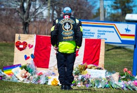 Former RCMP and naval officer Gerry White stands at attention in front of a memorial to fallen RCMP officer Const. Heidi Stevenson outside the Enfield RCMP detachment in Nova Scotia on Tuesday.