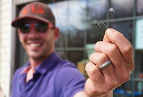Josh Lindsay holds a gold fish hook at Ben's Lake Campground in Belfast on May 28. It's similar to the one he used to start bartering for strange and higher value items.