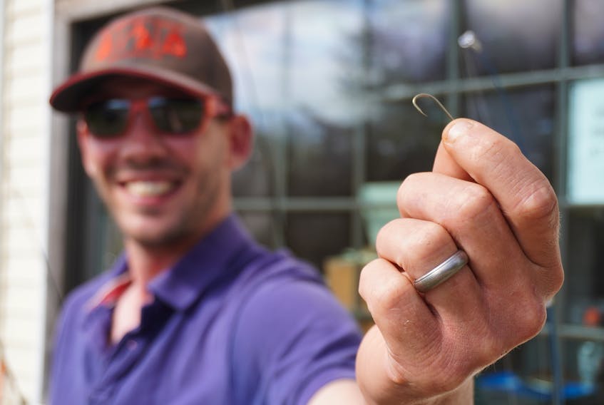Josh Lindsay holds a gold fish hook at Ben's Lake Campground in Belfast on May 28. It's similar to the one he used to start bartering for strange and higher value items.