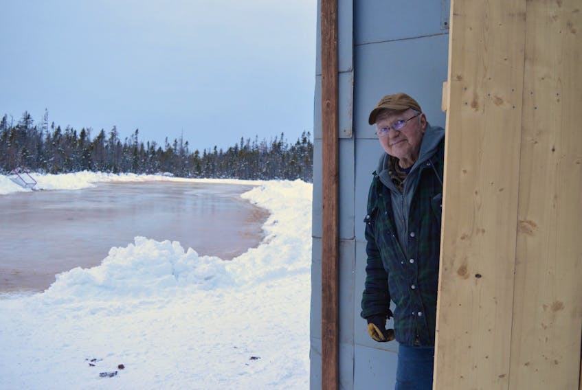 Wayne Getson takes a peek at the rink he's made in his back yard. The community is welcome to skate on the 34-by-200-foot rink.