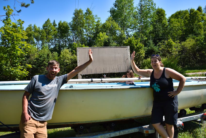 Josh Lindsay, owner of Ben’s Lake Campground, gives Valerie Vuillemot an air-high-five in front of her prize, while her daughter Alice inspects their winnings from inside the boat.