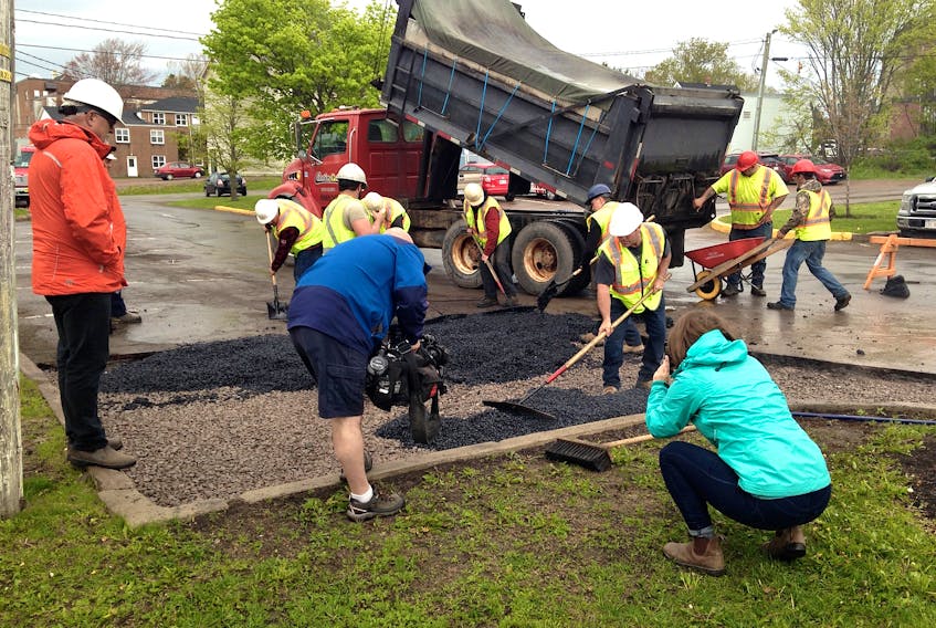 A crew from Dexter construction lays the permeable pavement down on Wednesday in this downtown parking lot.