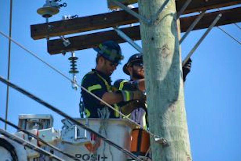 ['Jordan Bigelow, left, and Jeff Mahar, workers for City of Summerside electric department worked on a power lines after a single-vehicle accident knocked out power early Wednesday morning.']