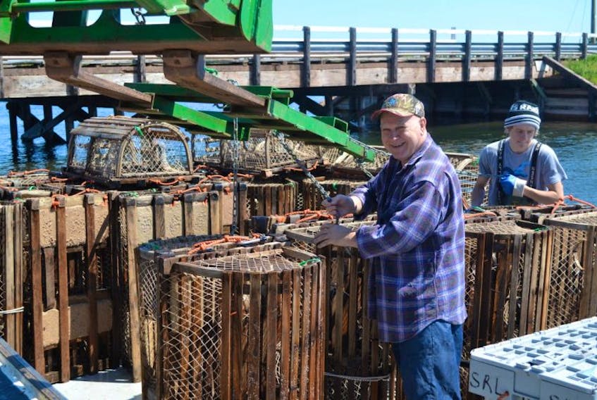 Crew member Garrett Aylward, right, gets a hand from volunteer Mike King in offloading lobster traps from Jamie Aylward’s vessel Thursday morning in Tignish. Thursday was the last day of the spring fishery, landing day, and the wharf quickly filled up with water-soaked traps.