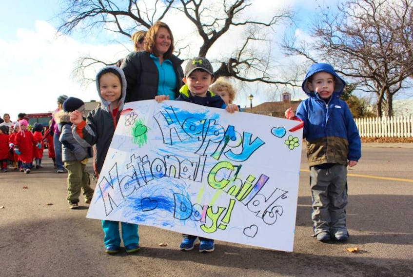 Cohen Spencer (left), Oliver Raynor and Cameron Waugh hold up a sign wishing everyone a happy national child day.