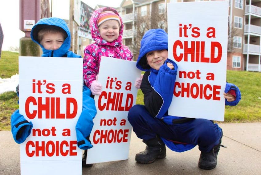 Jehu Rice (left), along with his sister Eternity and brother Sebastian, hold up signs during Saturday’s pro-life rally that took place on Roy Boates Avenue in Summerside.