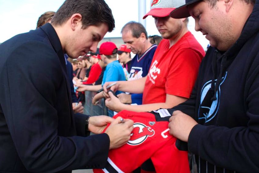 ['Ryan Mann, right, gets his daughter’s jersey signed by a New Jersey Devils player.']