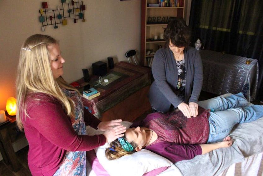 Lydia Pickering, left, and Sherry Yeo demonstrate a Reiki healing session on Rhonda Gill.