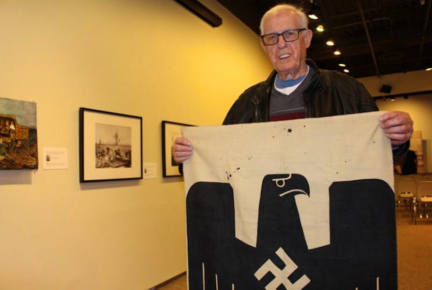 Ira Enman holds up the flag he traded a couple of cigarettes for, after the end of the Second World War.