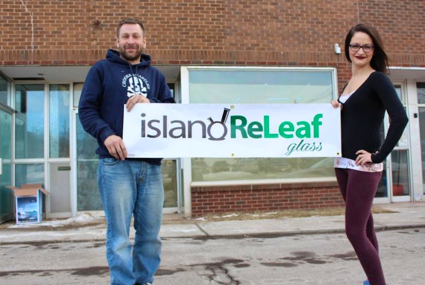 Tommy Biggar, left, and Megan Patey hold up their banner outside their storefront for Island Relief Glass in Summerside, located at 224 First Street.