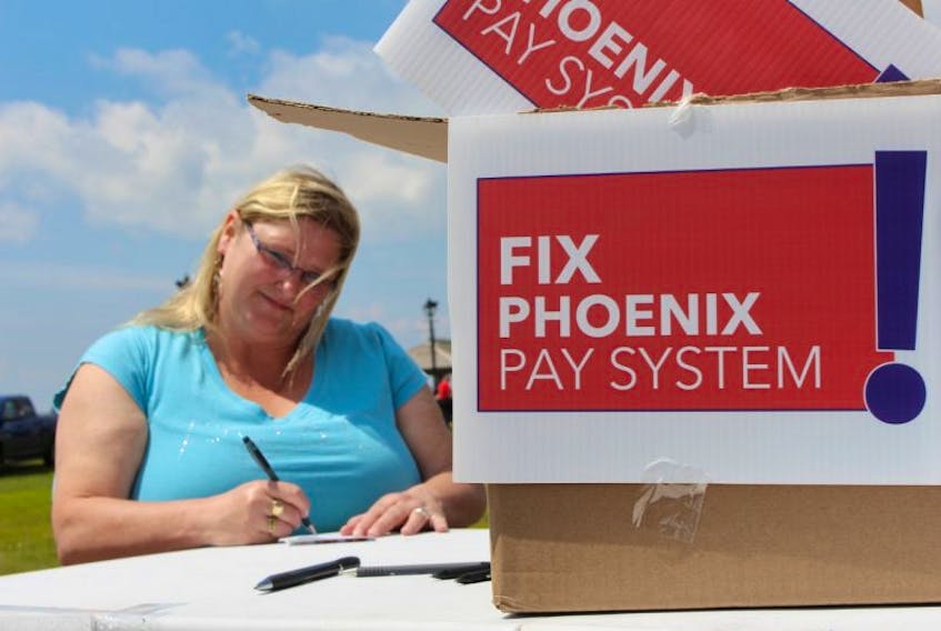 Heather Ford, spokesperson for PSAC P.E.I. chapter signs a postcard that will be sent to MP Scott Brison asking for the Phoenix pay system to be fixed.