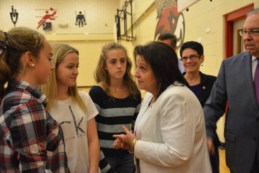 Rose-May Poirier, deputy chair of the Senate Standing Committee of Official Languages, right, chats with Grade 9 students Emma Dyer, left, Mya MacFarlane and Kate MacKenzie. 