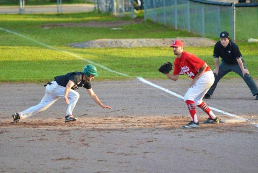 Mill River East native Jesse MacIntyre of the Charlottetown Gaudet’s Auto Body Islanders dives back into first base as the Chatham Ironmen’s Nick Leggatt awaits the throw while umpire Mike Richards of Summerside follows the play. The action took place in the first inning of Saturday night’s New Brunswick Senior Baseball League game at Queen Elizabeth Park’s Legends’ Field. The Islanders won the game 4-0.