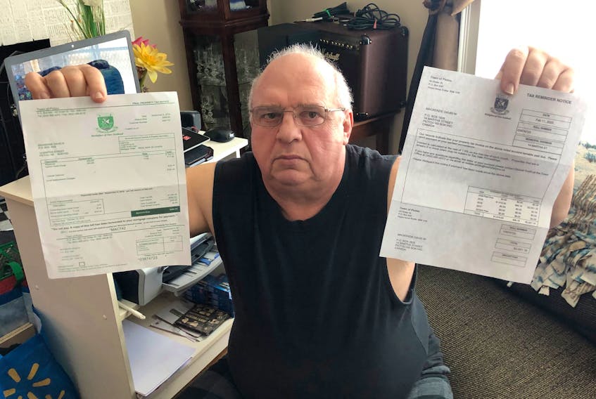 David MacKenzie holds copies of his tax bill which show how the town has added a charge of over $2,000 to his bill. ADAM MACINNIS/THE NEWS